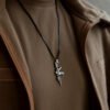 Close-up of a silver HK416 rifle pendant worn on a dark cord over a tan tactical-style fleece jacket.