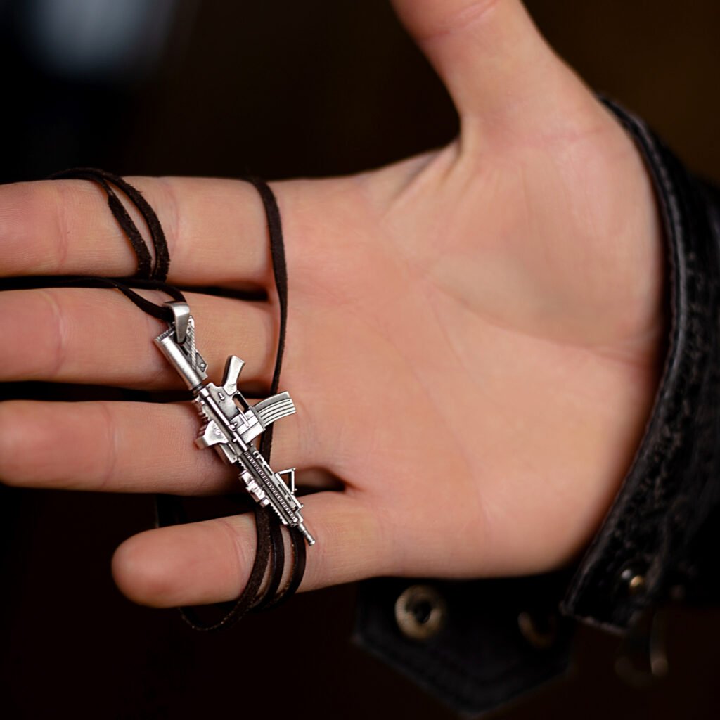holding a silver HK416 rifle pendant, with the dark leather cord