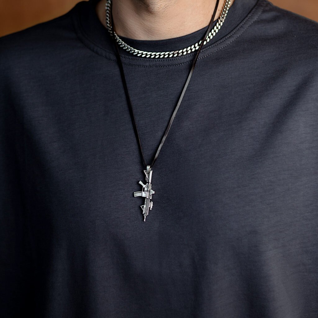 A silver rifle pendant worn on a dark cord